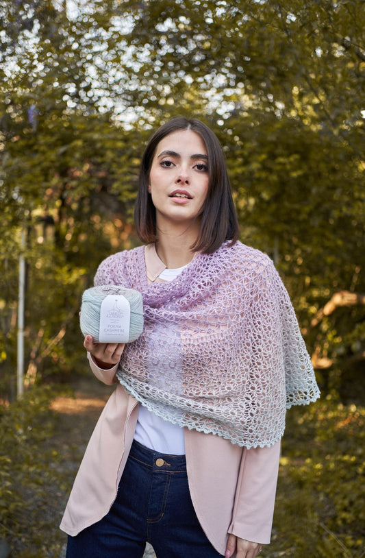 Woman in a lace shawl holding a yarn ball outdoors, showcasing Laines du Nord Poema Cashmere.